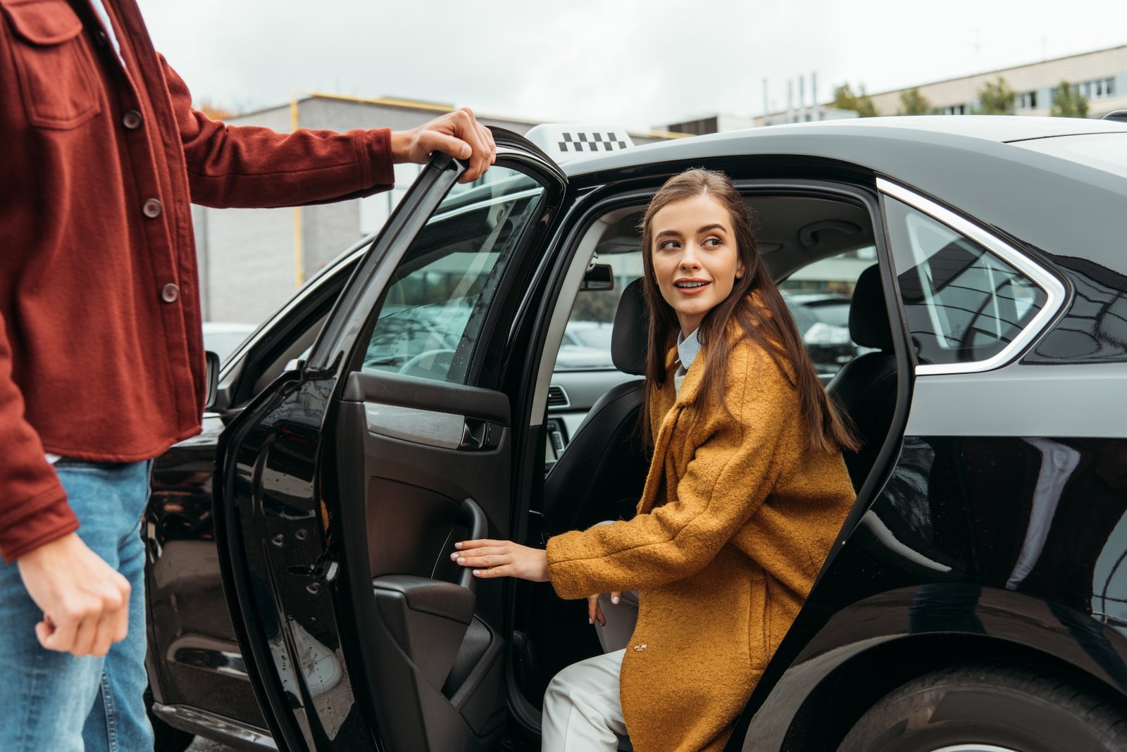 Taxi driver opening the car door for a smiling woman, showcasing courteous and professional private hire service.